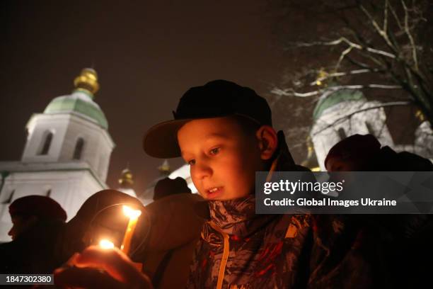 Boy holds a candle with the flame of the Light of Peace at Saint Sophia Cathedral on December 10, 2023 in Kyiv, Ukraine. Ukrainian scouts 'plastuny'...