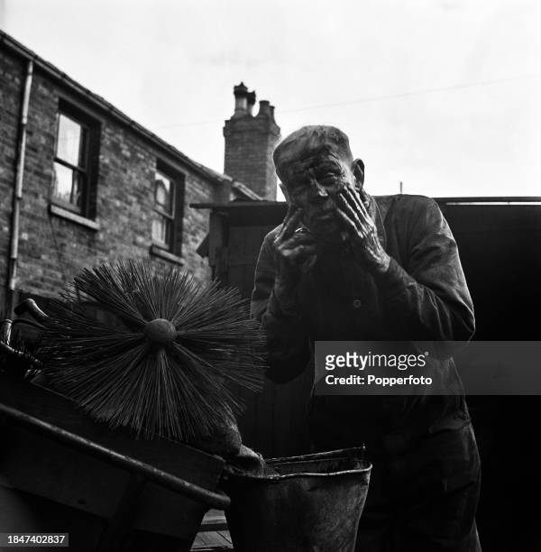 Chimney sweep Thomas Fowler washes his face from a bucket of water after a day's work cleaning chimneys in the city of Birmingham, England on 13th...