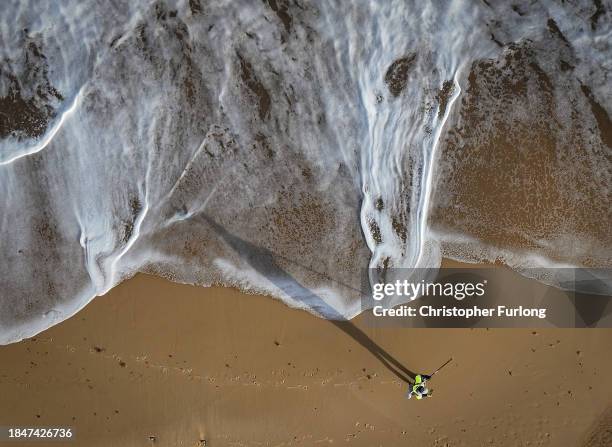 In this aerial view a land surveyor measures beach and sand erosion using GPS on Hemsby beach on December 11, 2023 in Hemsby, England. The collapse...