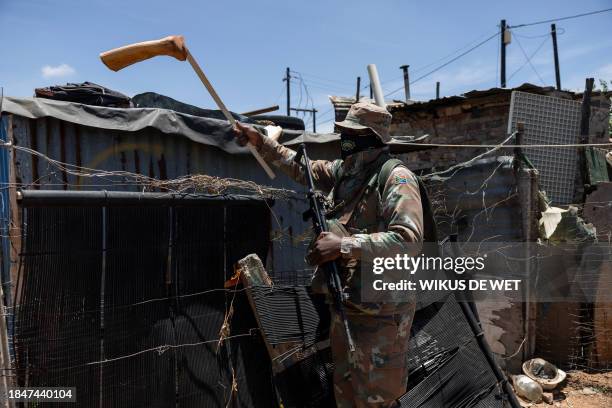 South African Defence Force soldier removes a boot from a roof of a structure during operation "Shanela" in the Soul City informal settlement near...