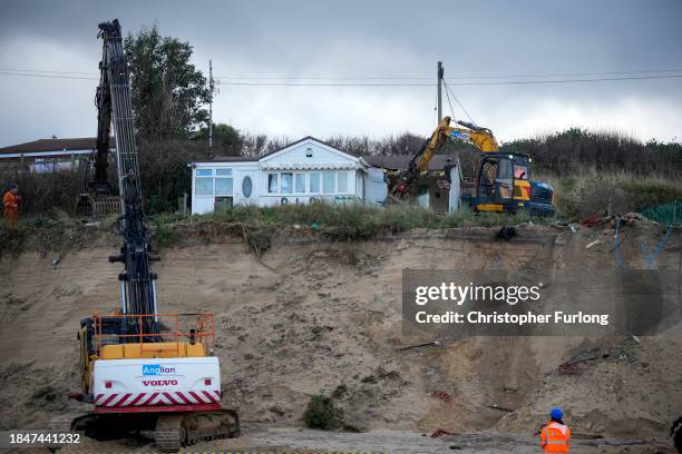 Beach chalet is demolished by workers before it falls down the sea cliff on The Marrams at Hemsby Beach on December 11, 2023 in Hemsby, England. The...