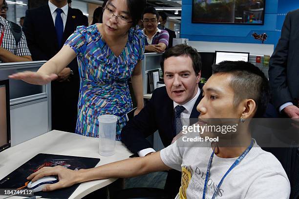 British Chancellor George Osborne watches a young designer creating a character for an on-line game at the Tencent headquarters on October 16, 2013...