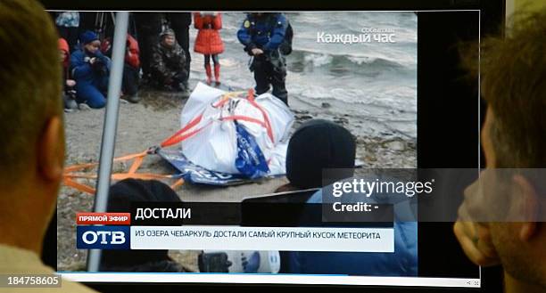 Men look in Moscow on October 16 at a computer screen displaying a team of divers pulling out a 1.5-metre-long suspected meteorite wrapped it in a...