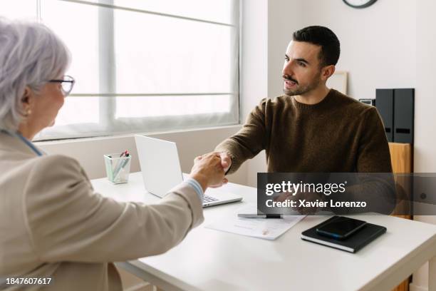 male hr recruiter shaking hand with mature female applicant during job interview. - job vacancy stock pictures, royalty-free photos & images