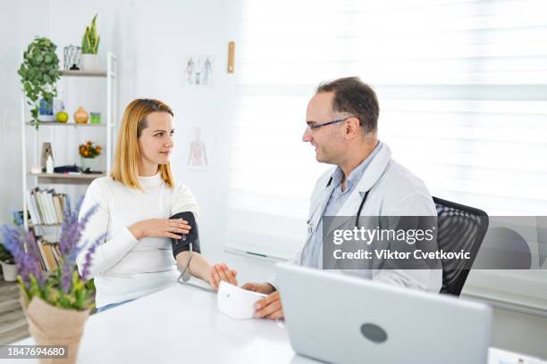 female patient having her blood pressure checked at the doctors office - ordination stock pictures, royalty-free photos & images
