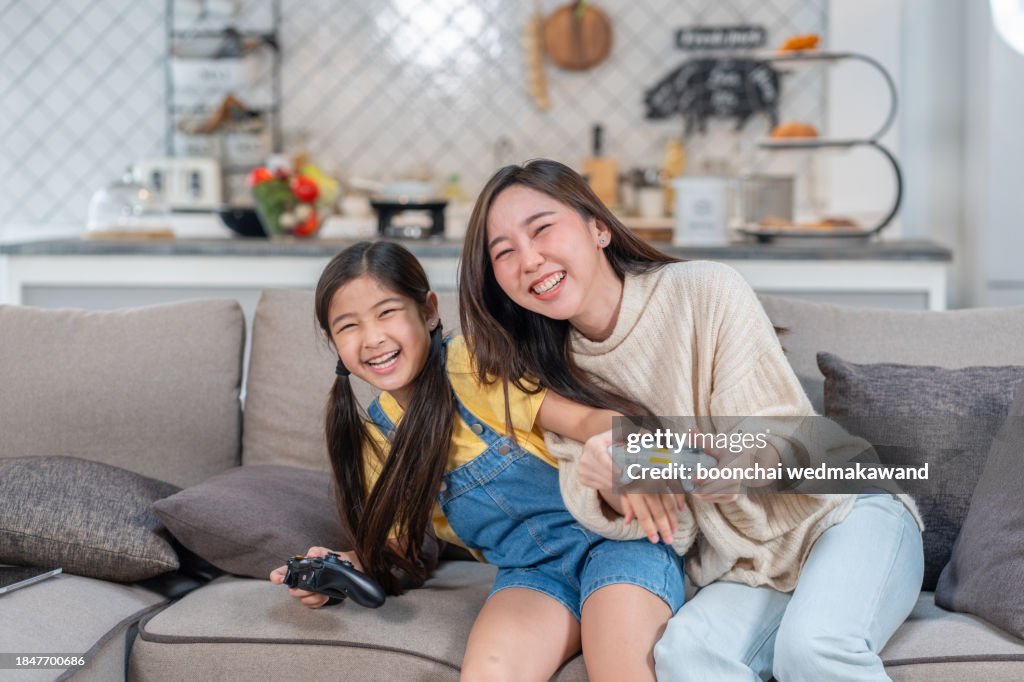 Candid of happy asian family play video game at home feeling excited fun holding console in hand in quarantine activity, entertainment at home concept. Competition and funny in leisure time or hobby.