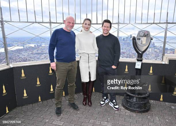 Simon Cellan Jones, Michelle Monaghan and Mark Wahlberg pose as the cast of Apple TV's “The Family Plan” visits the Empire State Building at The...