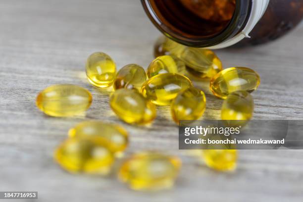 cod liver oil omega 3 gel capsules isolated on wooden background - huile de foie de morue photos et images de collection