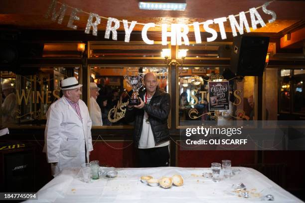 Publican and official 'Piemaster' Tony Callaghan presents competitor Ian Coulton with his trophy for winning the World Pie Eating Championships, held...