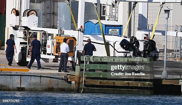 United States Coast Guard investigators look at a boat suspended on a boat lift at the United States Coast Guard Sector Station Miami after it...