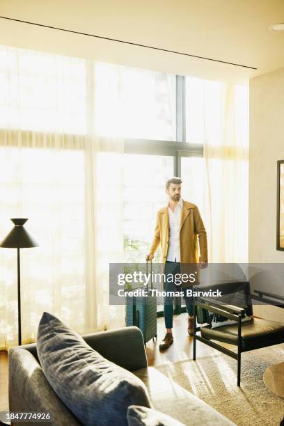 wide shot businessman walking through hotel suite with luggage - luxury hotel room stock pictures, royalty-free photos & images