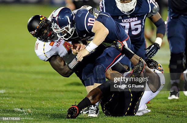 Chandler Whitmer of the Connecticut Huskies is sacked by Marcus Whitfield of the Maryland Terrapins at Rentschler Field on September 14, 2013 in East...
