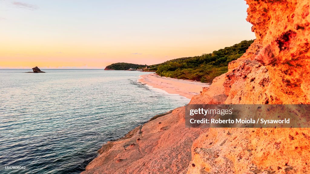 Sunset on cliffs along a pink sand beach