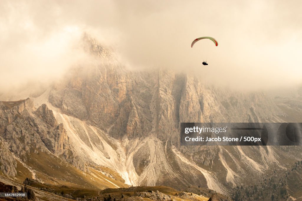 People paragliding over landscape against sky