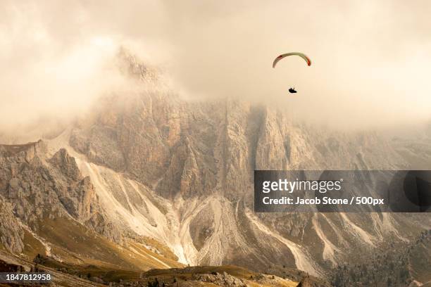 people paragliding over landscape against sky - paragliding stock pictures, royalty-free photos & images