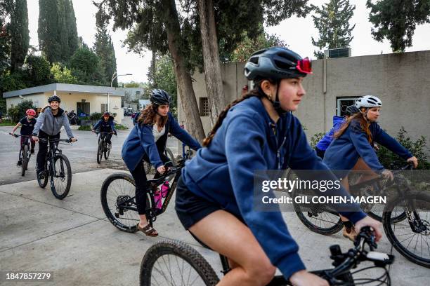 Teenagers from Kibbutz Nahal Oz ride bicycles in Kibbutz Mishmar Haemek in northern Israel on December 12, 2023. Kibbutz Nahal Oz was supposed to...