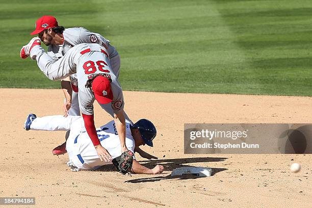 Pete Kozma of the St. Louis Cardinals turns a double play alongside teammate Matt Carpenter as Mark Ellis of the Los Angeles Dodgers attempts to...