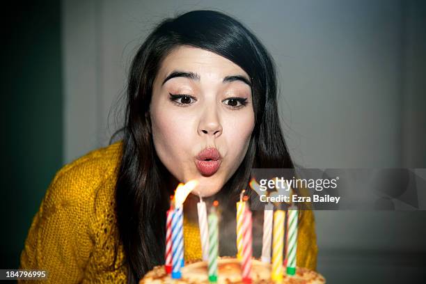 mixed race woman blowing out birthday candles - birthday cake stock pictures, royalty-free photos & images