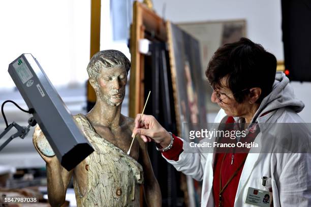 Restorer works on a wooden sculpture at Vatican Museums Restoration Laboratory during “Beyond the surface. The restorer's gaze": the exhibition...