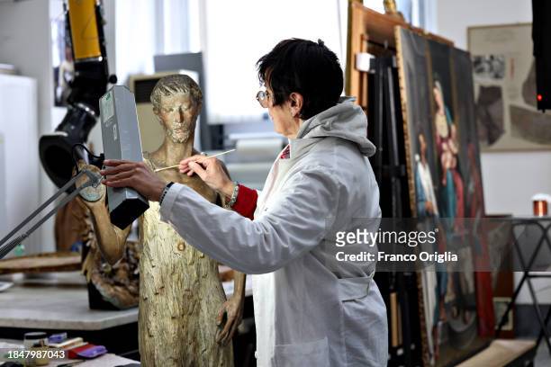 Restorer works on a wooden sculpture at Vatican Museums Restoration Laboratory during “Beyond the surface. The restorer's gaze": the exhibition...