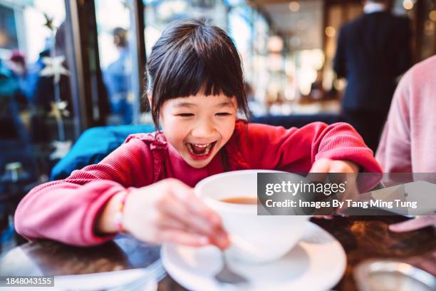 happy girl enjoying traditional afternoon tea with her family in restaurant - tea shop stock pictures, royalty-free photos & images