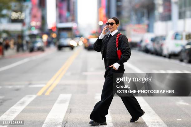 fashionably dressed female business person seen on the street of new york talking on the phone and smiling - new york black and white stock pictures, royalty-free photos & images