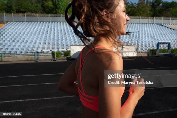 a young woman runs in the stadium. sports lifestyle. training. run. active and healthy lifestyle. - sprint-sport-wettbewerbsform stock-fotos und bilder