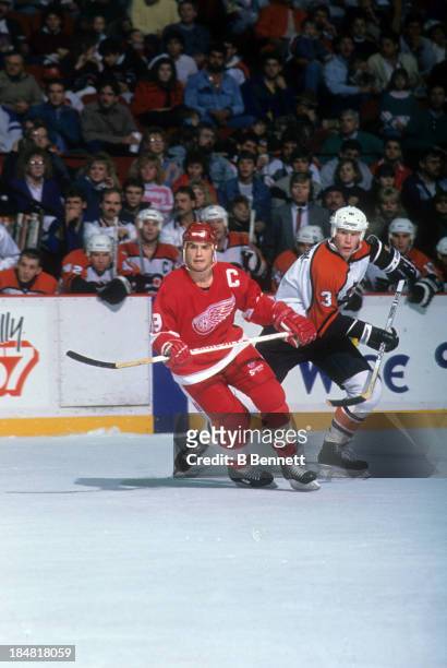 Steve Yzerman of the Detroit Red Wings skates on the ice as Gord Murphy of the Philadelphia Flyers follows behind on January 15, 1989 at the Spectrum...