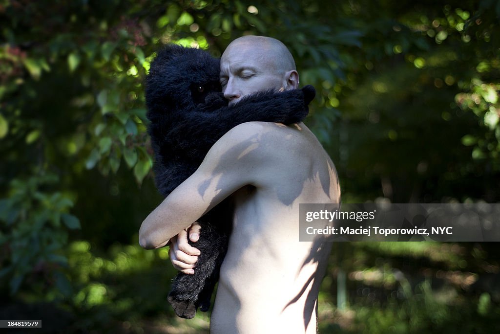 Shirtless man hugging a stuffed gorilla toy