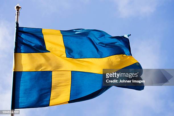 swedish flag against blue sky - schweden stock-fotos und bilder