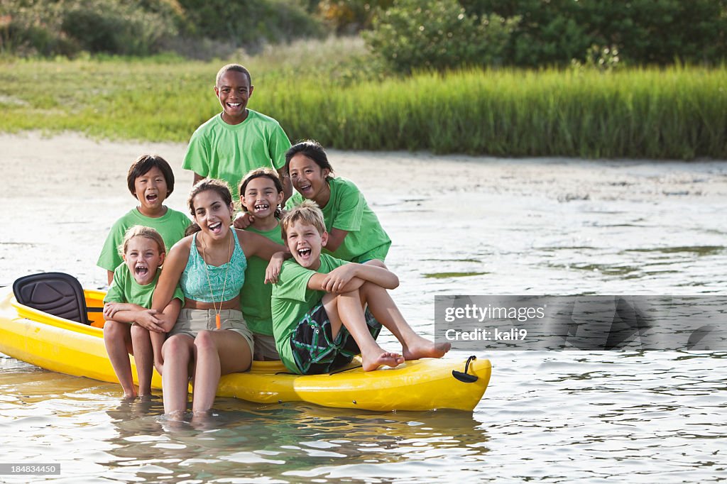 Summer camp counselor and children sitting on kayak