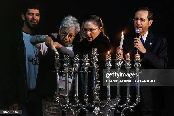 President Isaac Herzog and his wife first lady Michal Herzog assist an elderly family member of one of the hostages held by Palestinian militants...