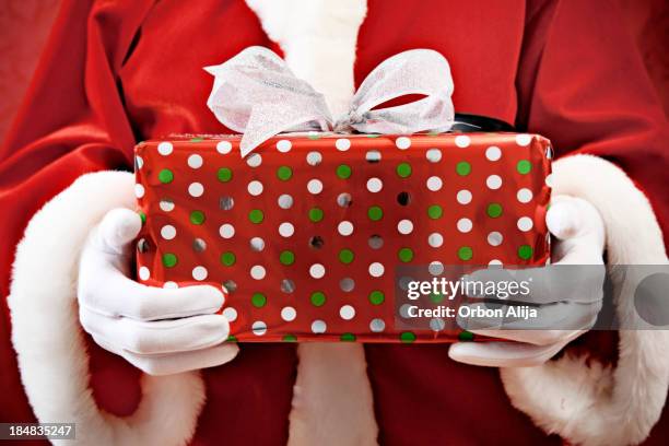 santa holding a gift - santa giving out presents stock pictures, royalty-free photos & images