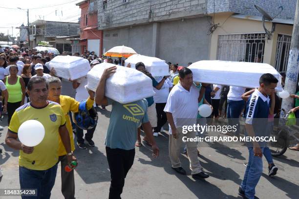 Relatives and friends carry the coffins of four children killed by gunmen during their funeral in Guayaquil, Ecuador, on December 14, 2023. Four...