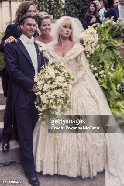Harry Hamlin and Nicollette Sheridan pose for the camera on their wedding day with best man Kenny G. And the maid of honor standing behind them as...