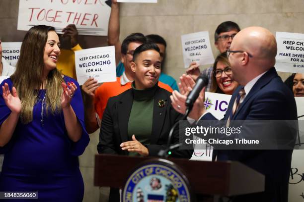 Ald. Jeylu Gutierrez, 14th, left, and Ald. Michael Rodriguez, 22nd, right join immigrant advocates in cheering for Ald. Jessie Fuentes, 26th, at a...