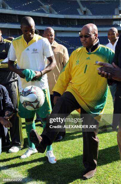 South African President Jacob Zuma juggles with the ball next to South African team player and captain Aaron Mokoena in Soweto on June 13, 2009 on...
