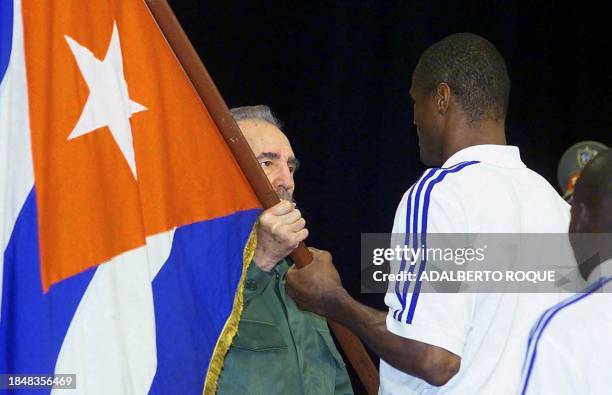 Cuban President Fidel Castro presents a Cuban flag to boxer Felix Savon as the Cuban delegation to the 2000 Olympics in Sydney participates in a...