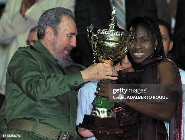 Cuban President Fidel Castro gives a trophy to Cuban volleyball player Mireya Luis during a fairwell ceremony 02 March 2001 in Havana, Cuba. El...