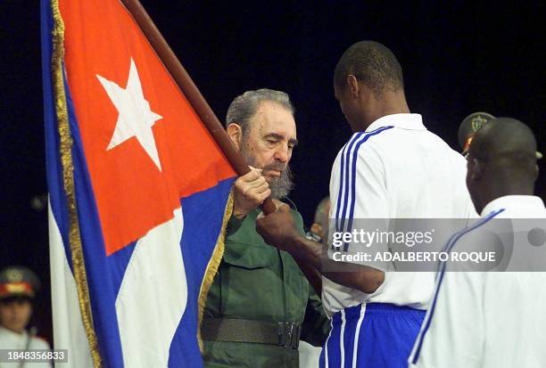 Cuban President Fidel Castro presents a Cuban flag to boxer Felix Savon as the Cuban delegation to the 2000 Olympics in Sydney participates in a...