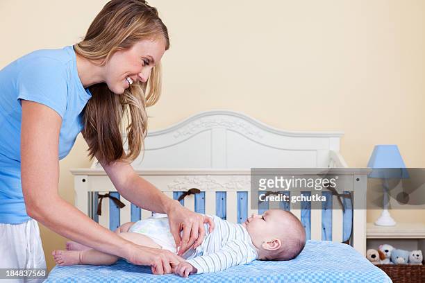 mother changing baby diaper - gchutka stock pictures, royalty-free photos & images