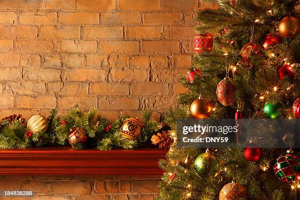 christmas tree in front of mantel piece adorned with bough - mantelpiece stock pictures, royalty-free photos & images