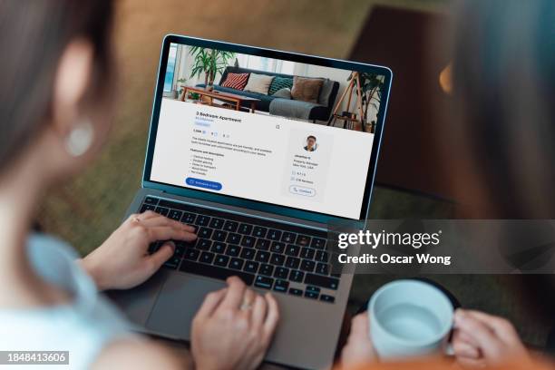 over the shoulder view of woman looking at real estate listing on laptop - over the shoulder view stock pictures, royalty-free photos & images
