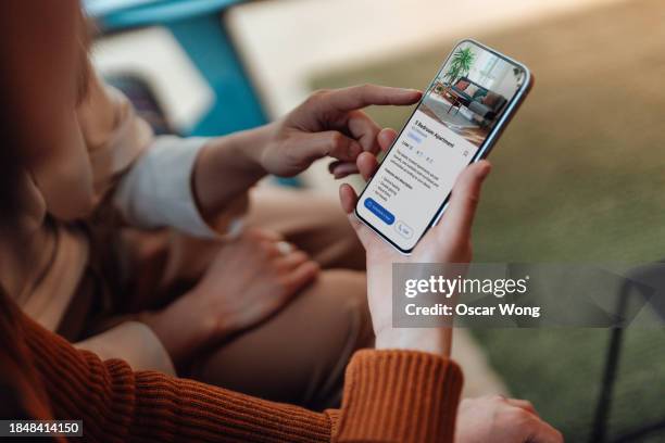 over the shoulder view of woman looking at real estate listing on smartphone - inquadratura da sopra le spalle foto e immagini stock