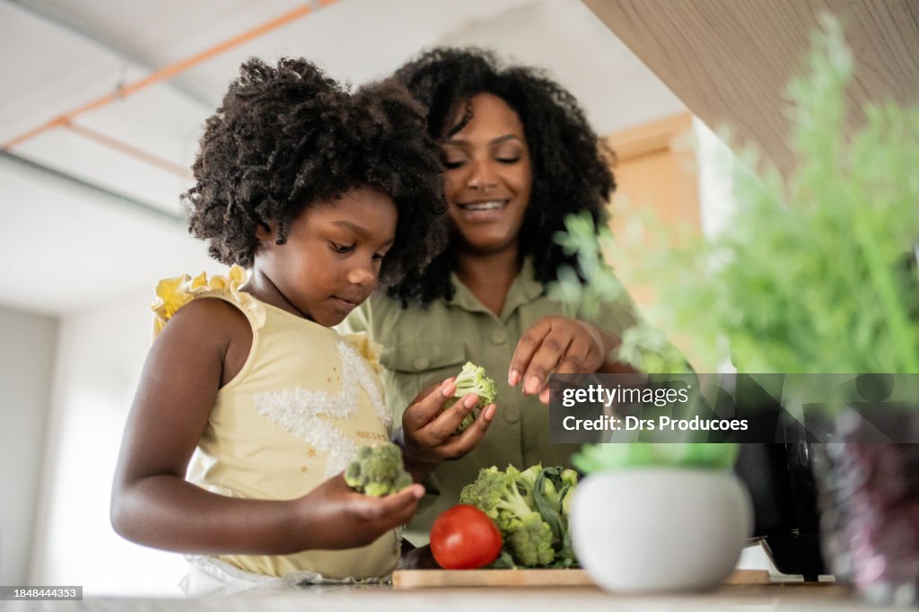 Mother teaching daughter how to prepare vegetables