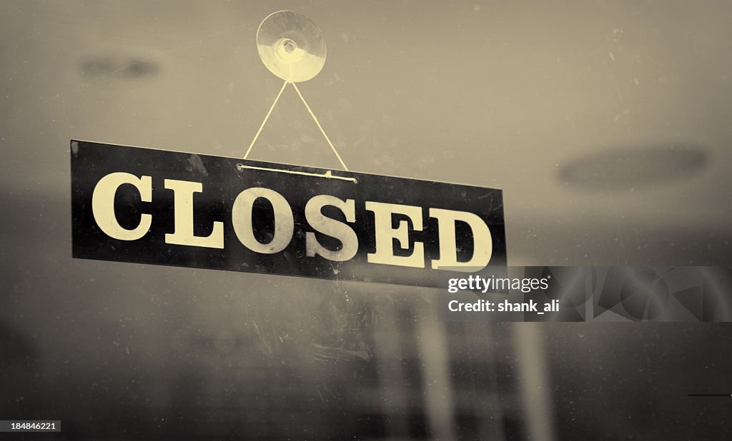 Black and white closeup of a Closed sign hanging on a window