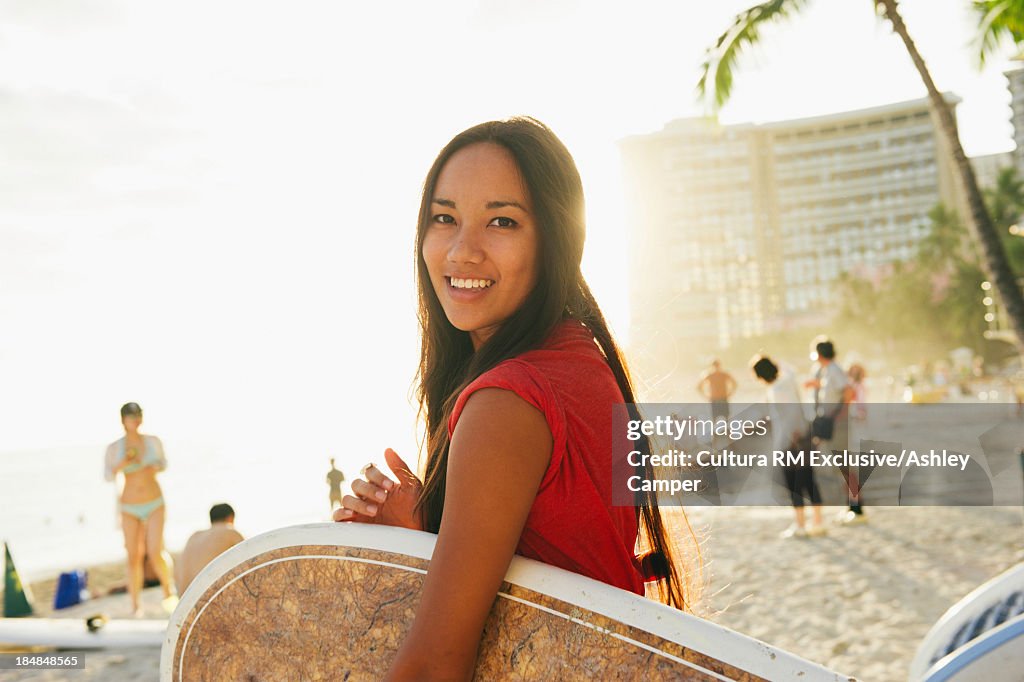 Young woman carrying bodyboard, Honolulu, Hawaii