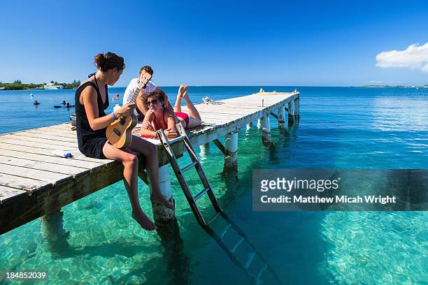 girls play music in the sun on a utila dock. - utila honduras stock pictures, royalty-free photos & images