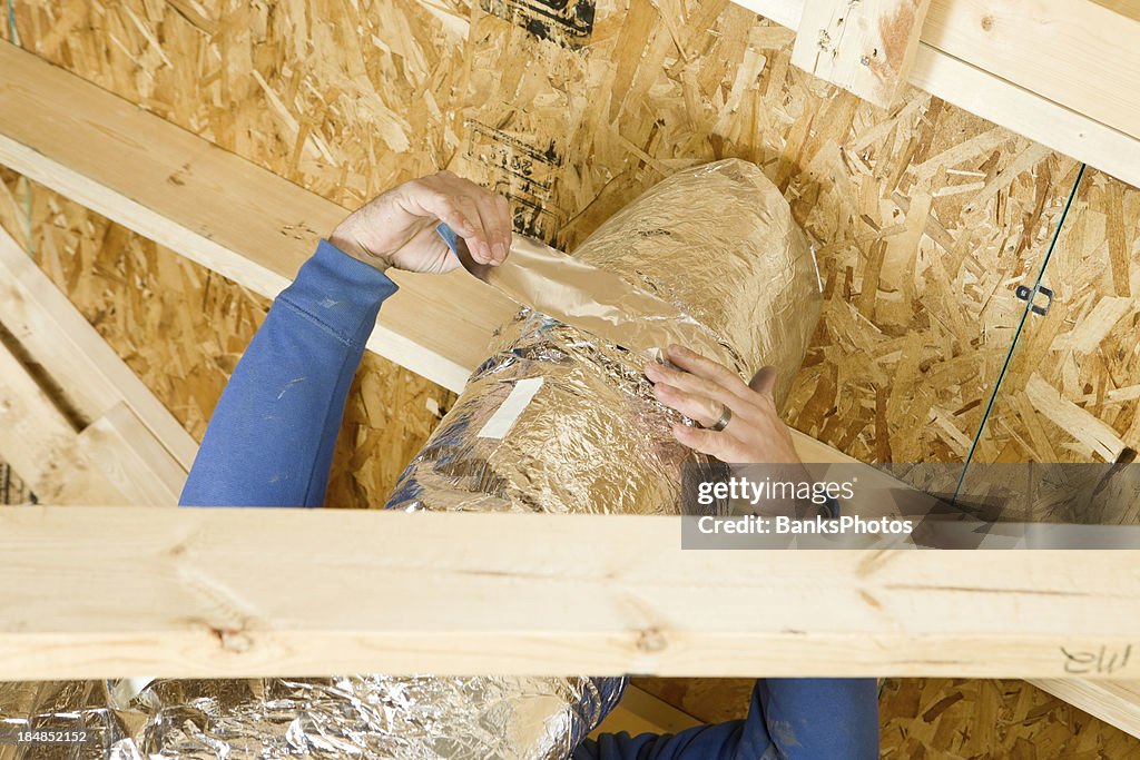 Trabalhador de isolamento de duto de respiro sótão com papel alumínio fita