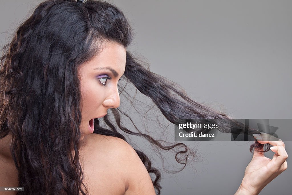 A woman who is surprised by her damaged hair